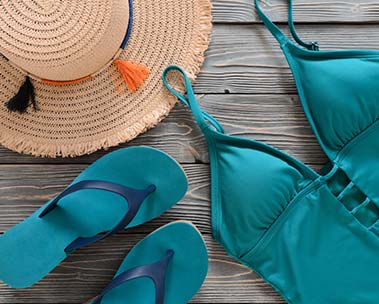 Tan straw hat, blue one piece swimsuit and flip flops