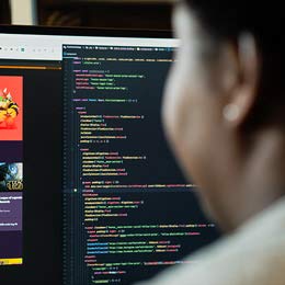 A woman looks at a computer screen filled with computer code.