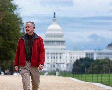 A man walks with the U.S. Capitol in the background.