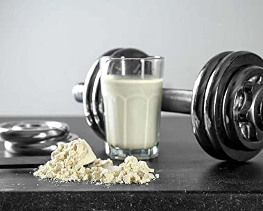 Nutritional shake in glass next to exercise weights