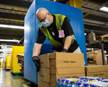 Man wearing mask closing up a box of donated supplies