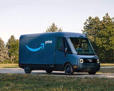 Electric Amazon delivery van driving down the road.