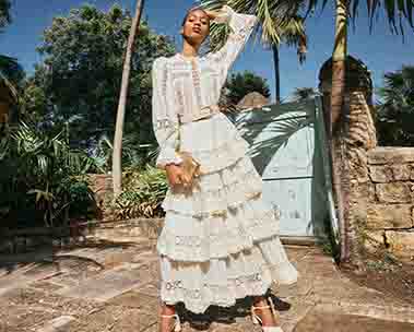 Girl in long white dress in front of palm trees