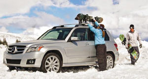 Woman removing snowboard from a Thule 575 Snowboard Carrier Rooftop Rack