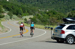 Cyclists using the Thule 9025 Apex four-bike hitch mount carrier during a ride
