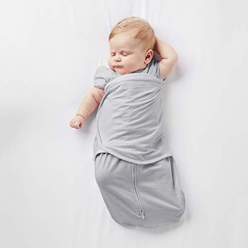 Child sleeping in a cotton baby wrap carrier on parent's hip.