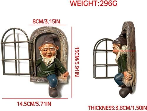 Garden gnome hanging on a tree branch in a backyard.