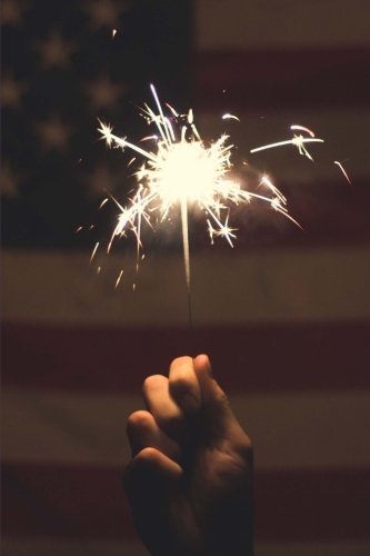 A sparkler on the fourth of july and the american flag …