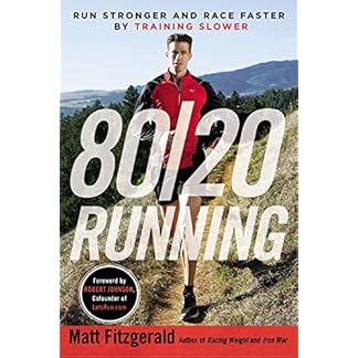 Cover of the book 80/20 Running: Run Stronger and Race Faster by Training Slower by Matt Fitzgerald. The cover shows a male runner on a trail in the outdoors, wearing a red and black running outfit, with mountains and greenery in the background. The title is in bold white text across the center, and a circular black label notes a foreword by Robert Johnson, cofounder of LetsRun.com. The author's name is at the bottom in bold yellow text.