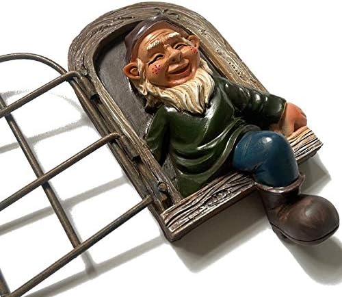 Colorful gnome statue holding a watering can, placed under a tree in a backyard setting.