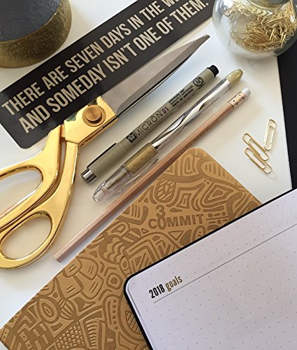 Commit30 Planner abierto a lado de algunos clips, tijeras, plumas y otros artículos de oficina. Se alcanza a ver un letrero con la frase 