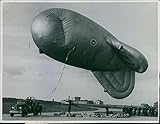 Vintage photo of 1940Officers standing and looking the barrage balloon, flying and tied by stone.