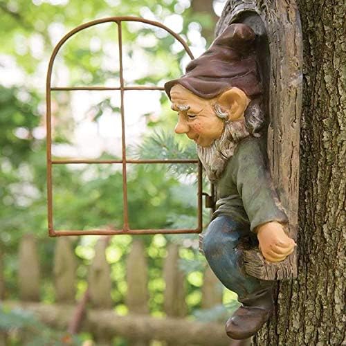Garden gnome hanging on a tree branch in a backyard setting.