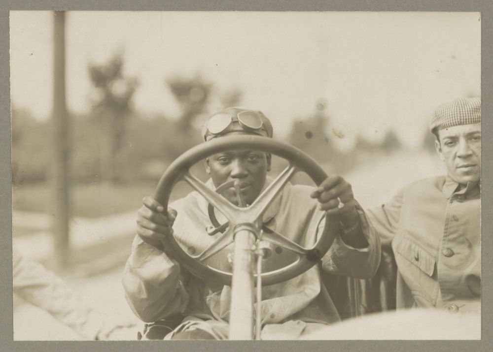Photographs - 1910 Photo Champion Jack Johnson at wheel of his 90 horse power Thomas Flyer Jack Johnson looking through the steering wheel of his Thomas Flyer automobile, with another man seated next to him.