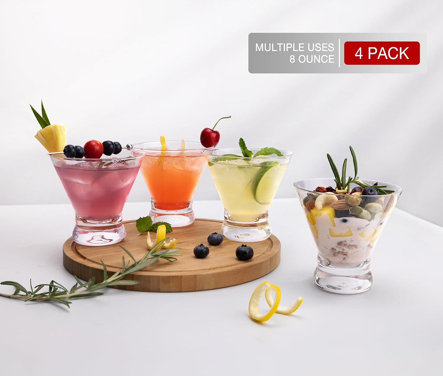 four stemless coupe cocktail glasses on a round wooden board each holding a different garnished drink