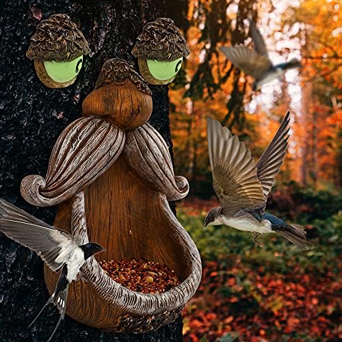 Dark bird feeder hanging from a backyard tree with eyes design.