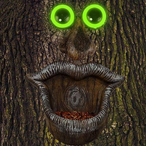 Tree face sculpture with eyes as bird feeders and mouth as a feeding tray.
