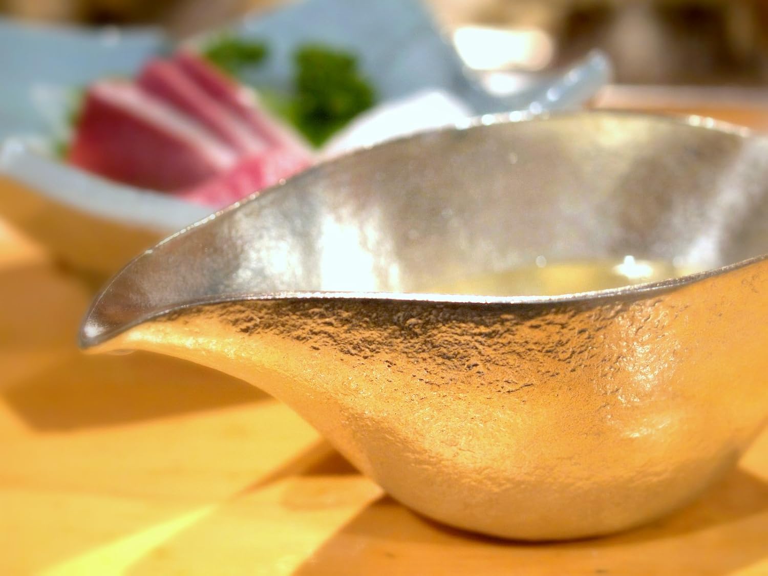 錫の酒器と刺身がテーブルに並んでいる様子