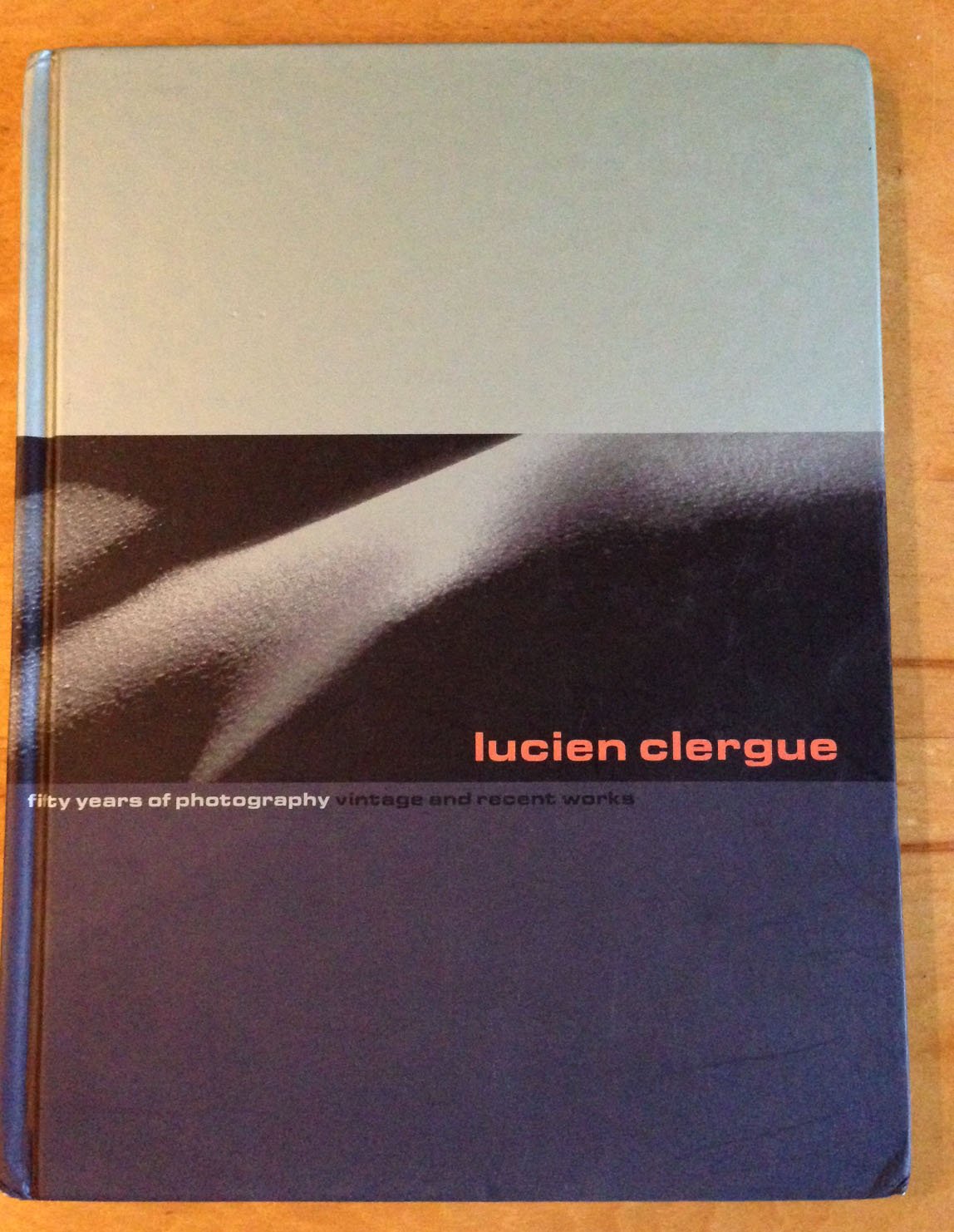 Cover Art for the book Lucien Clergue: Fifty Years of Photography: Vintage and Recent Works, with three horizontal monochrome bands. The center band appears to be an unfocused shape like a sand dune.