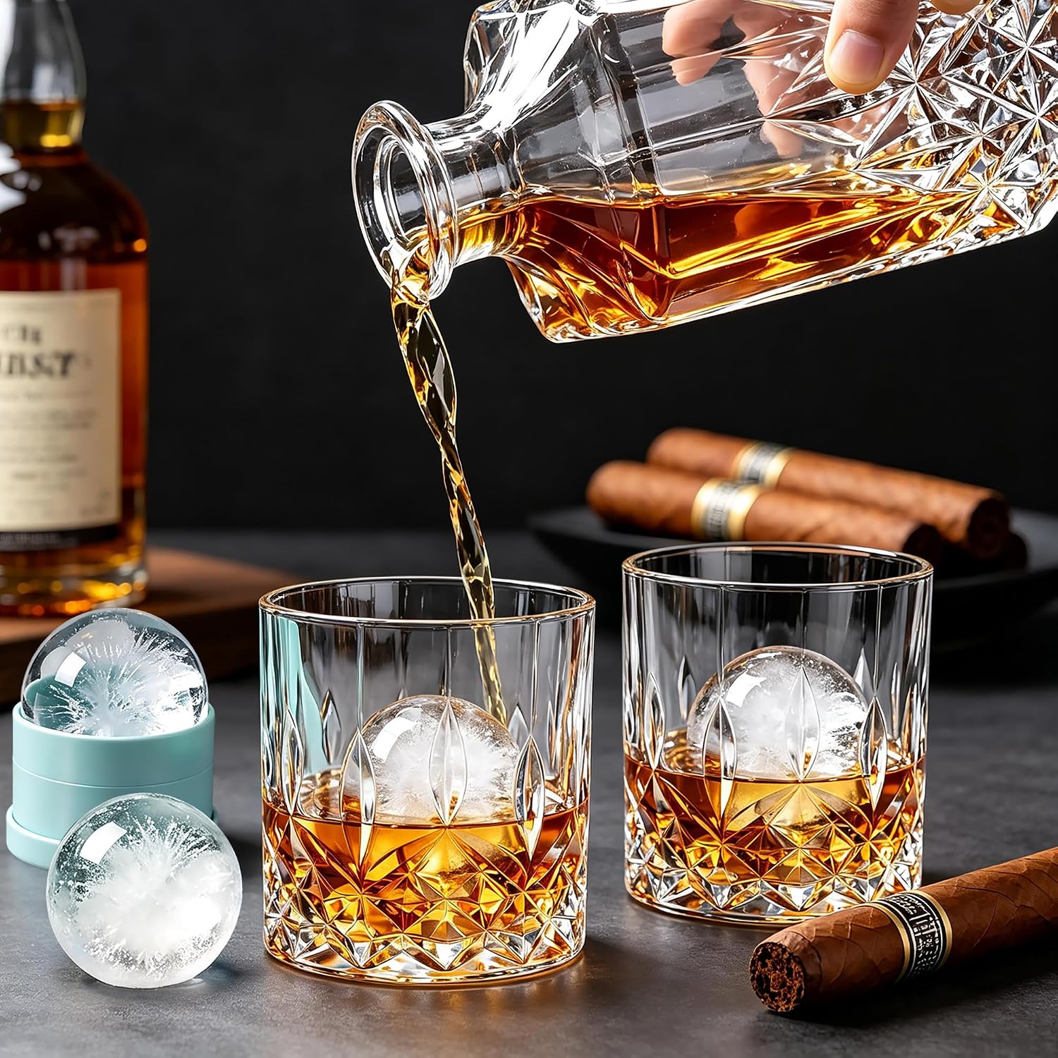 whiskey being poured into an engraved rocks glass on a dark table with a bottle behind and cigars resting alongside