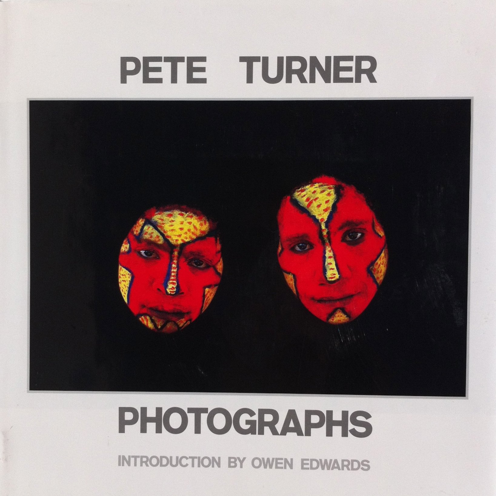 Cover Art for the book Pete Turner Photographs, showing a pair of faces painted in red and yellow, surrounded by a black background.