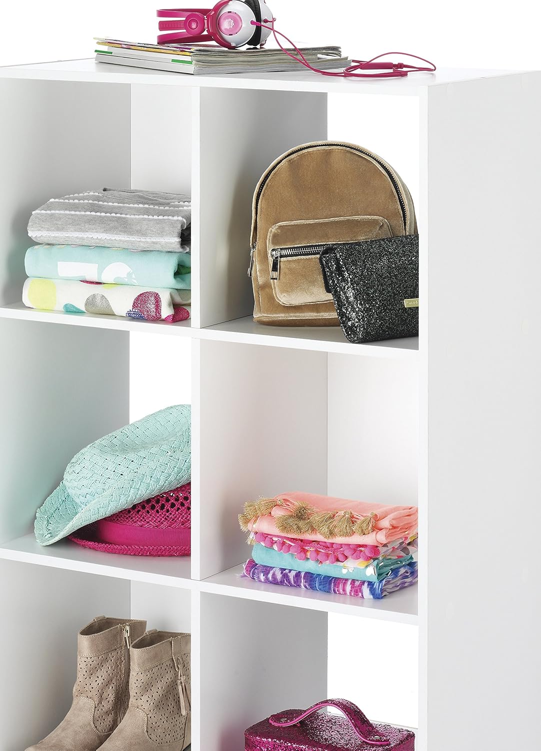 A white shelving unit with six cubes holding a variety of clothing, purses and shoes. 