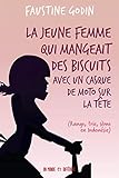 La jeune femme qui mangeait des biscuits avec un casque de moto sur la tête La jeune femme qui mangeait des biscuits avec un casque de moto sur la tête