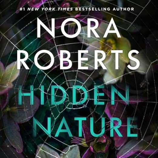 The title and author name are superimposed on a spiderweb that lays on top of out of focus flowers and leaves. 