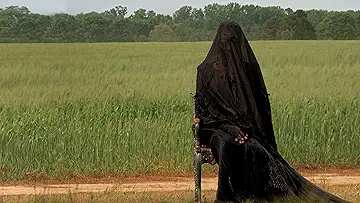 A mysterious silhouette stands in a dark yard, creating an ominous atmosphere in the poster for The Woman in the Yard game.