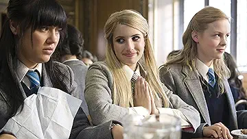 Emma Roberts as Poppy Moore stands in her school uniform at Abbey Mount boarding school in the Wild Child game.